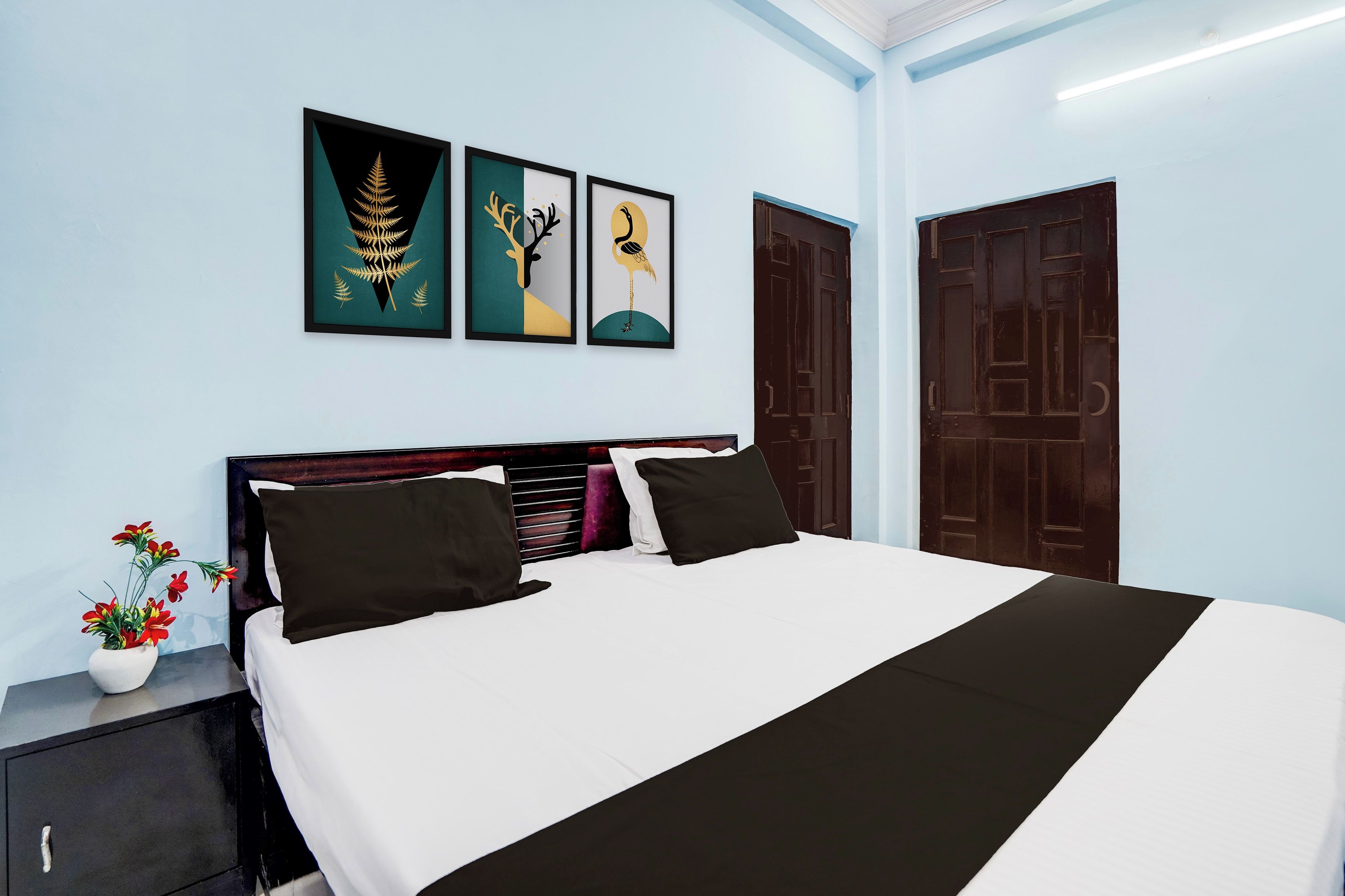 Een hotelkamer met een bed, een nachtkastje en drie ingelijste kunstwerken aan de muur.