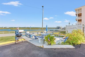 A waterfront deck with picnic tables and a barbecue grill. - Couples Getaway 105 -1BR Gold Coast, Cherry Grove (North Myrtle Beach)