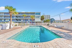 Ein rechteckiger Swimmingpool mit einem tiefenbegrenzungszeichen für 8 Fuß, umgeben von einer Holzterrasse und einem weißen Zaun.
