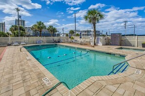 A swimming pool with a lifeguard sign, palm trees, and a fenced area with lounge chairs. - Couples Getaway 105 -1BR Gold Coast, Cherry Grove (North Myrtle Beach)