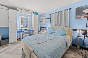 Ein Schlafzimmer mit Bett, Nachttisch, Lampe und Schreibtisch mit Stuhl.