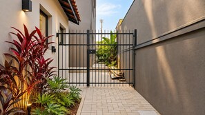 A gated entrance to a building with a paved pathway and potted plants. - STUDIO 04 (Vinhedo)