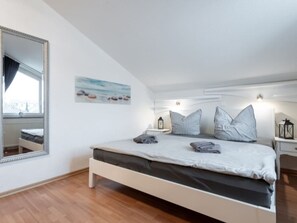 Ein Schlafzimmer mit einem großen Bett, einem Nachttisch mit einer Laterne, einem Wandspiegel und einem Gemälde.
