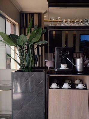 A modern kitchen with a coffee machine, a potted plant, and a wine rack. - Q's Boutique Stay (Standerton)