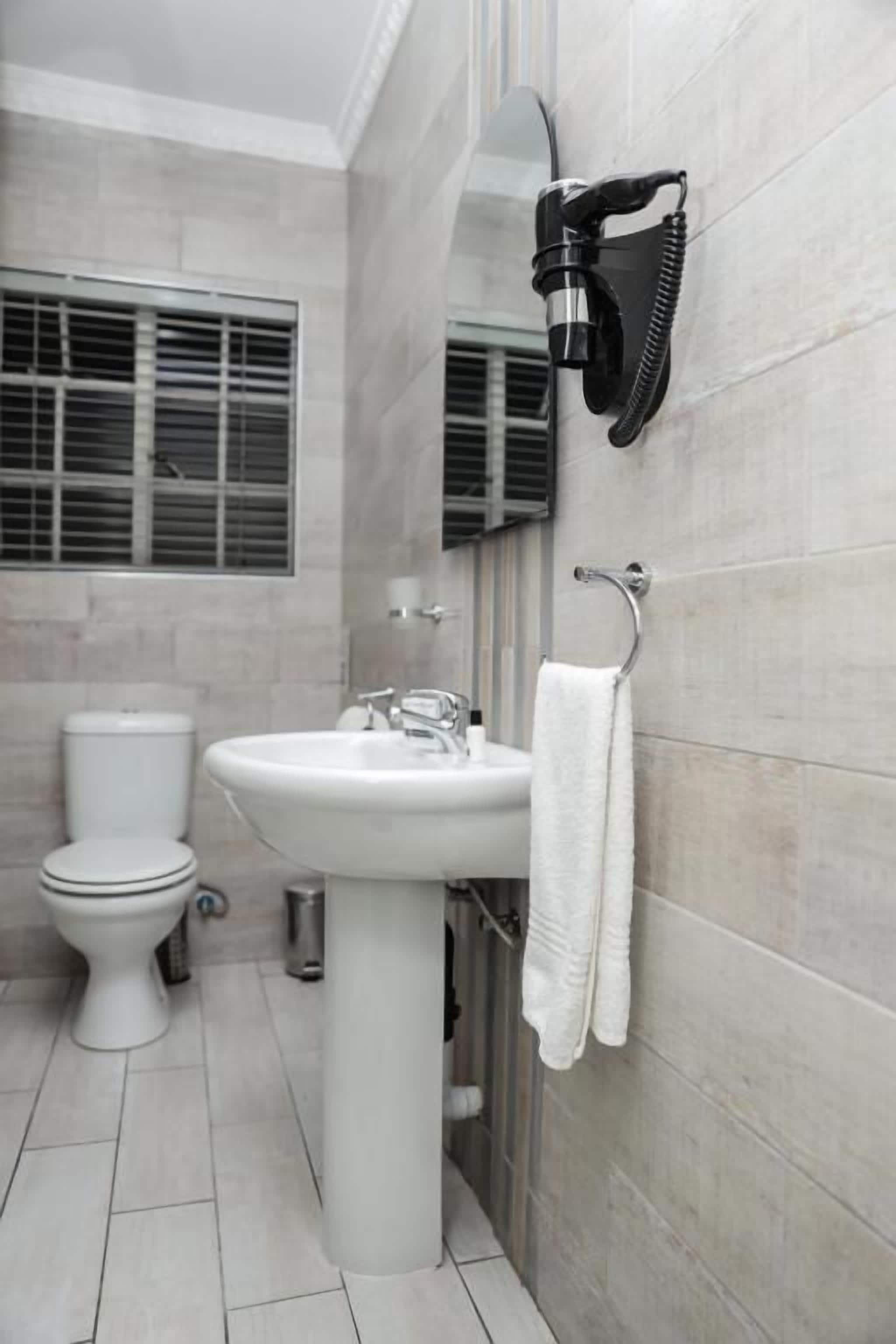 Un baño con inodoro, lavamanos y perchero para toallas.
