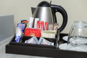 Un safataix amb sobres de cafè, una tetera i un got.