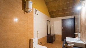Une salle de bain comprenant des toilettes, un bidet, un lavabo, un miroir et un chauffe-eau fixé au mur.