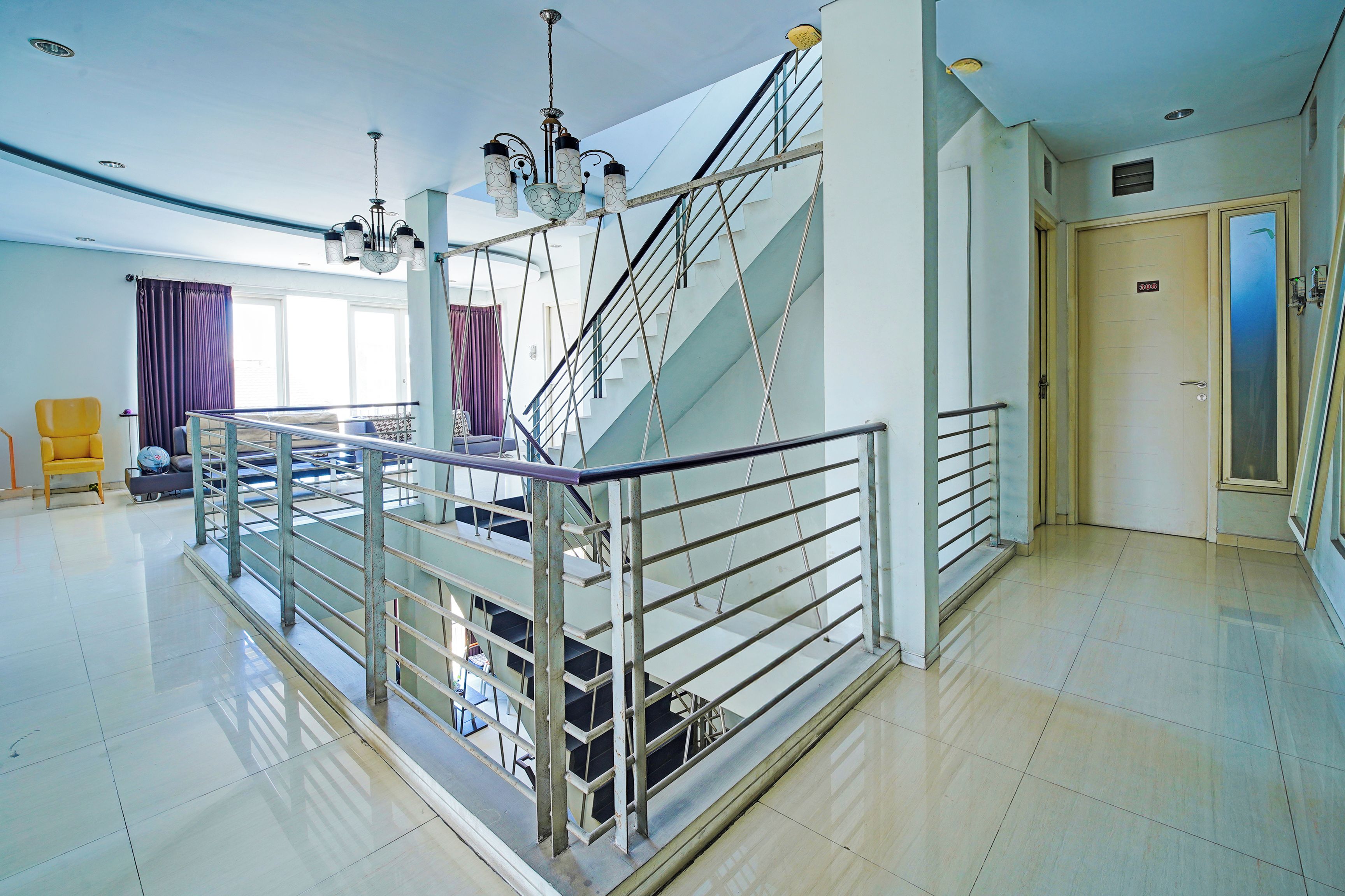 A spacious hotel lobby with a staircase, a chandelier, and a door marked '308'.
