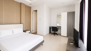 A hotel room with a large bed, a desk with a chair, a television, and a bathroom visible through an open door. - Hotel O near Mall Panakkukang (Makassar)