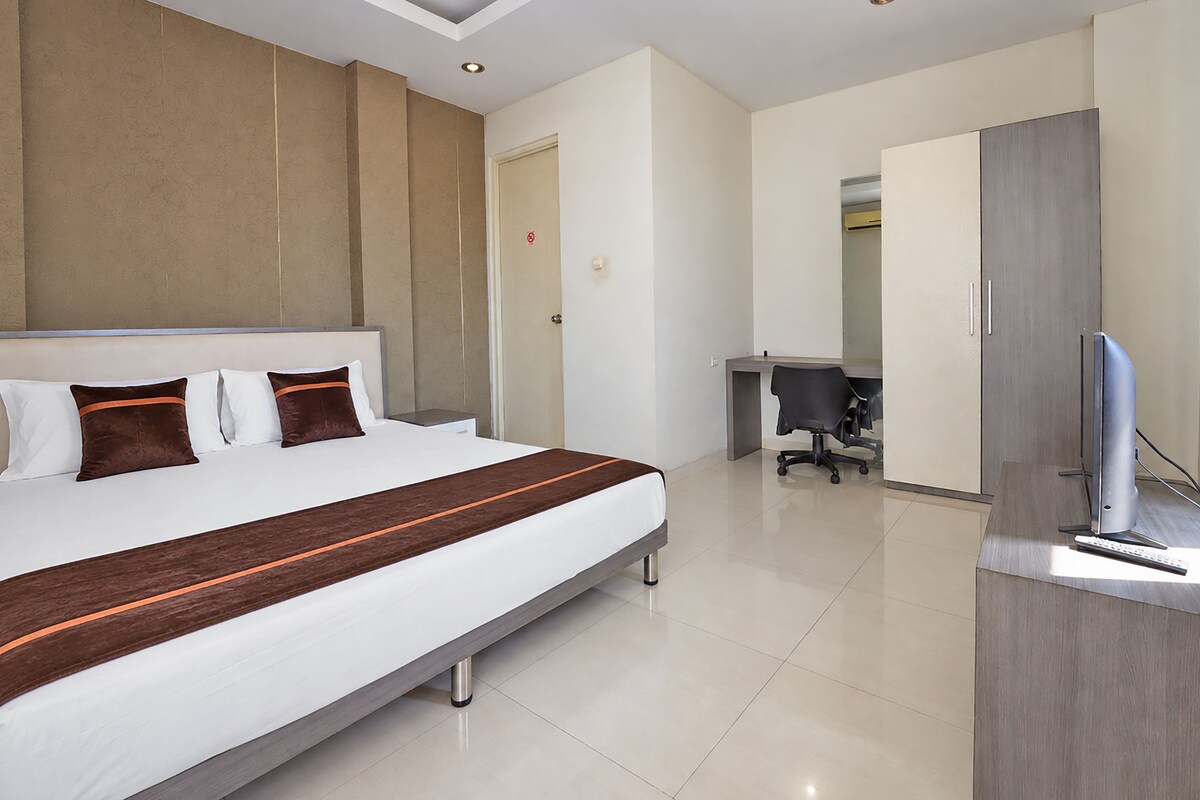Een moderne hotelkamer met een groot bed, een bureau en een televisie.