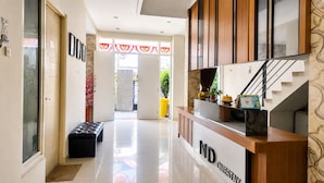 A hotel reception area with a wooden counter, a bench, and a staircase. - Hotel O near Mall Panakkukang (Makassar)