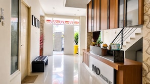 A hotel reception area with a wooden counter, a bench, and a staircase. - Hotel O near Mall Panakkukang (Makassar)