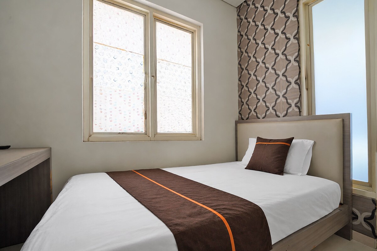 Een hotelkamer met een bed, een raam en een behang met patroon.
