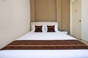 Een hotelkamer met een bed, nachtkastje en een deur.