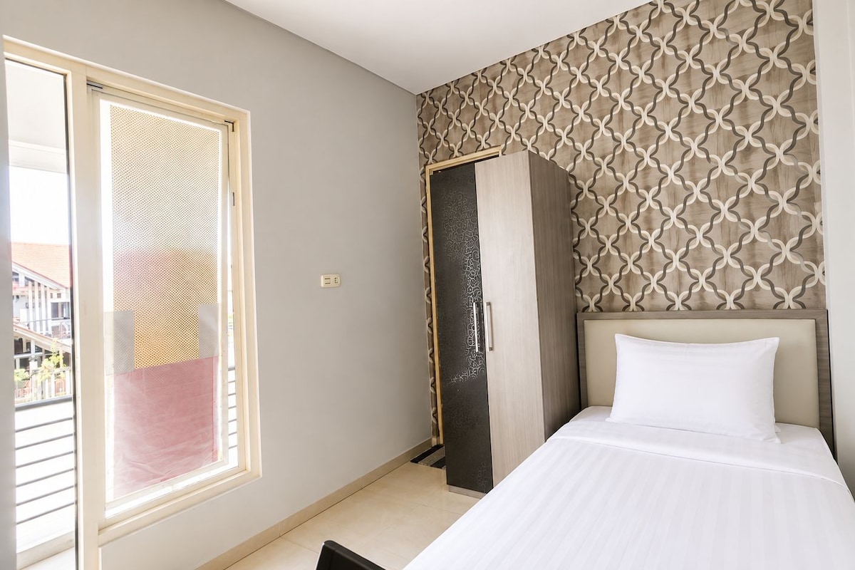 A hotel room with a bed, a wardrobe, and a patterned wall.
