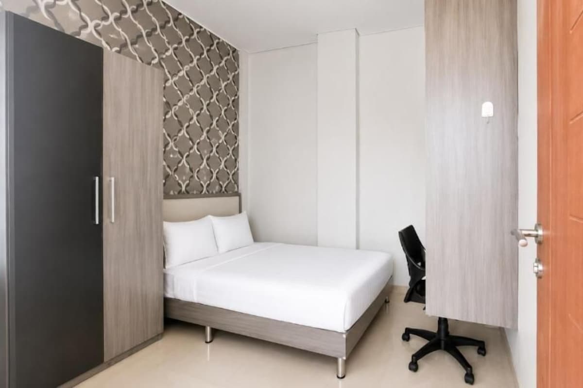 A bedroom with a bed, a desk, and a wardrobe.