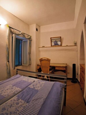 A bedroom with a bed, a chair, a desk, and a shelf with a picture. - Holiday Home With 3 Bedrooms (Pietrabruna)