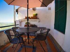 A terrace with a round table and chairs, a potted plant, and a view of the landscape. - Holiday Home With 3 Bedrooms (Pietrabruna)