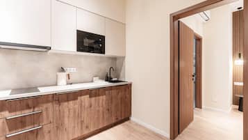 Cocina moderna con armarios de madera, microondas integrado y encimera con hervidor y dispensador de jabón.