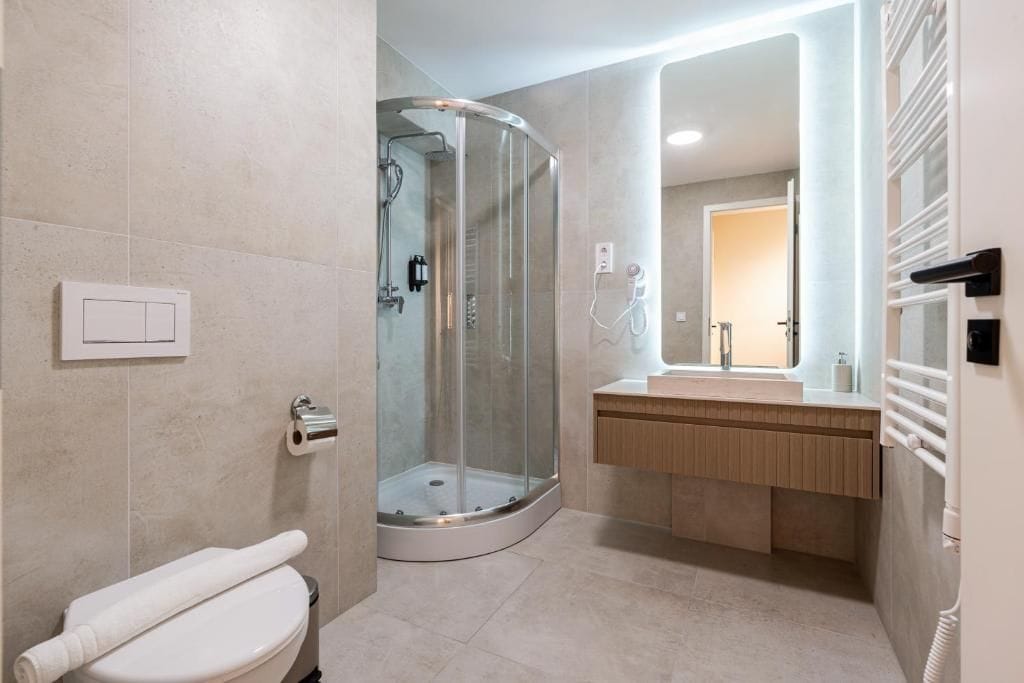 A modern bathroom with a glass-enclosed shower, a toilet, and a vanity with a mirror.