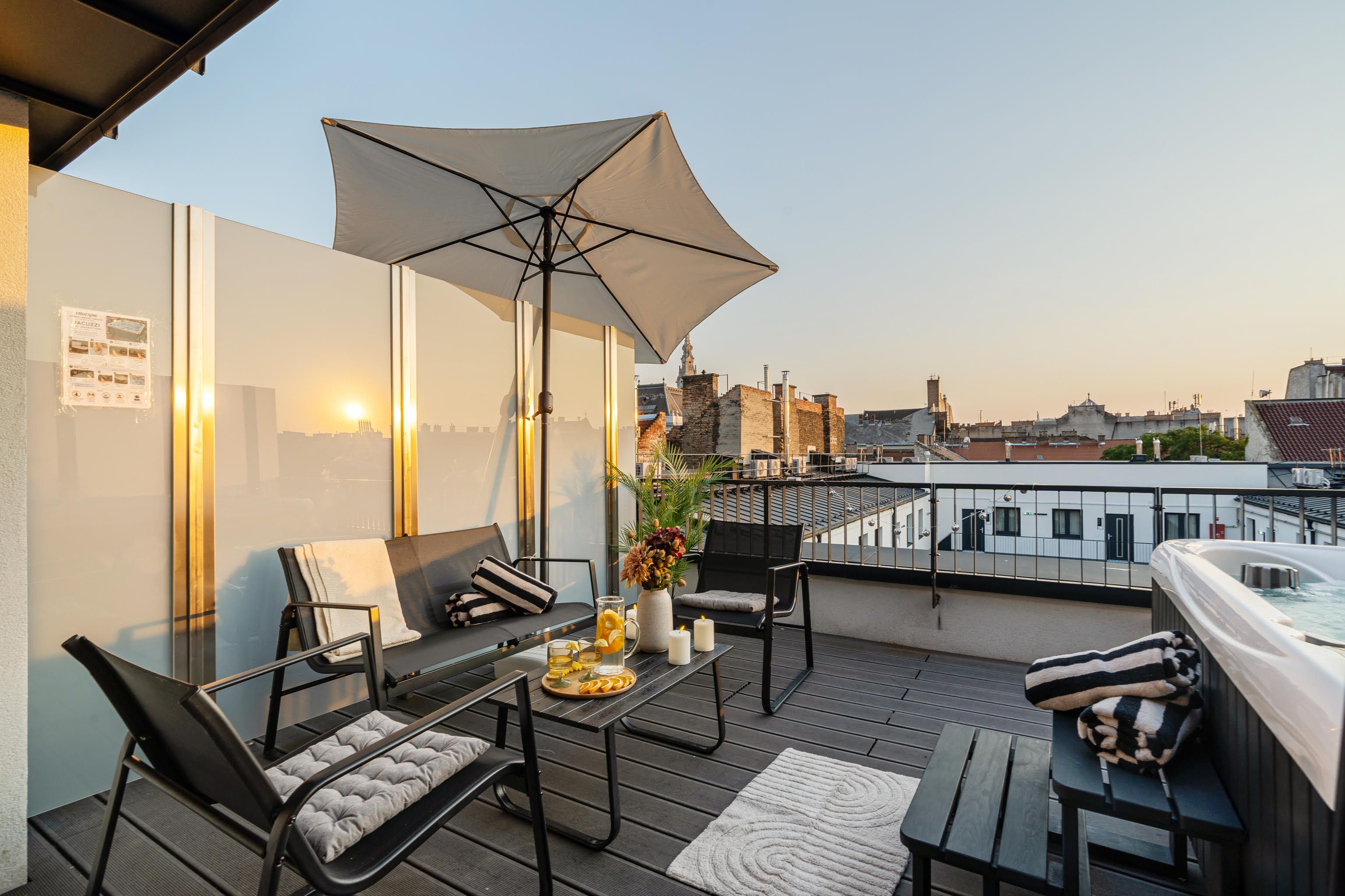 Een terras op het dak met een zitgedeelte, een hottub en uitzicht over de stad.