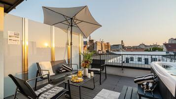 Een terras op het dak met een zitgedeelte, een hottub en uitzicht over de stad.