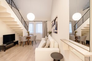 Una sala de estar moderna con sofá, televisor y un comedor con sillas y mesa.