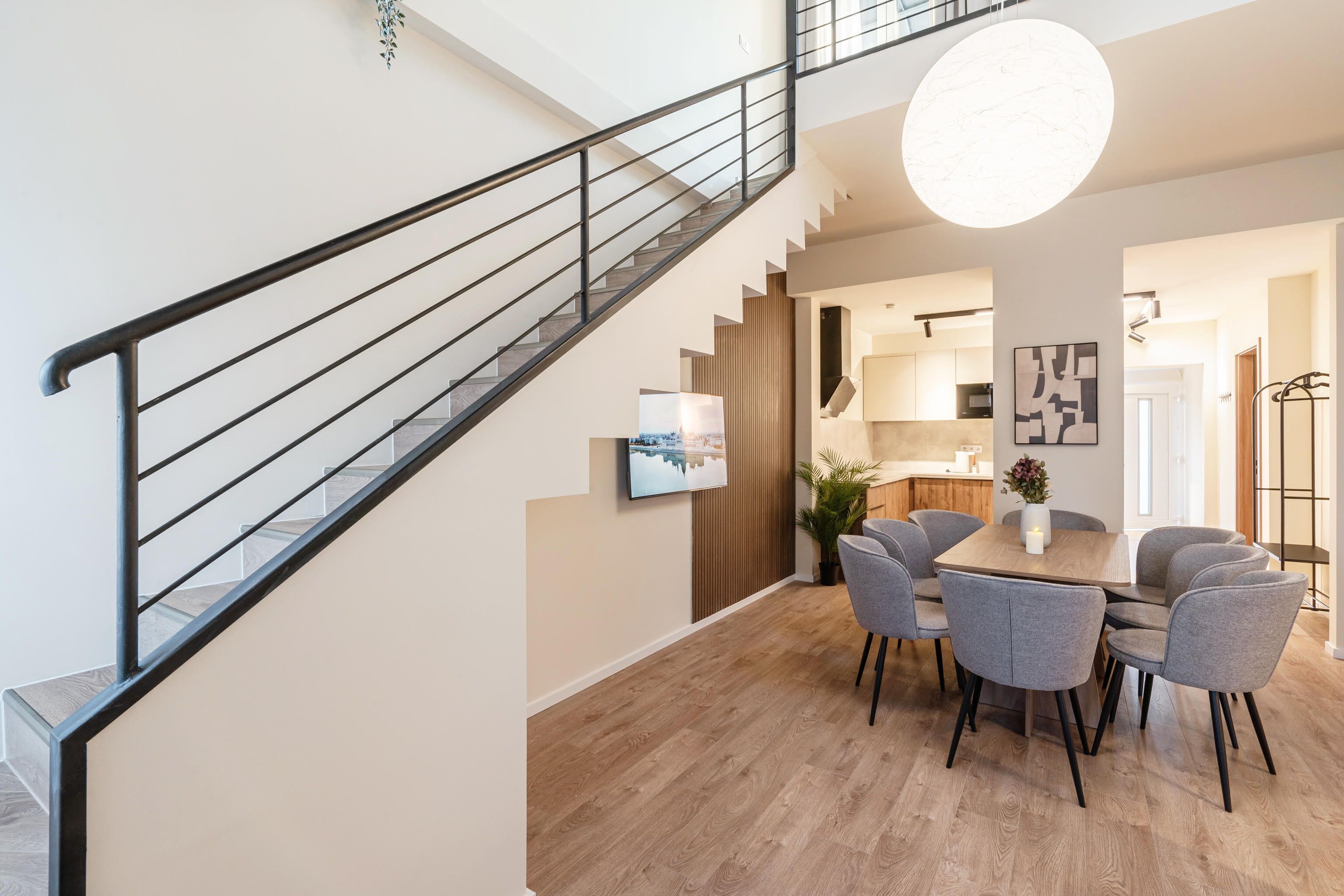 A modern interior with a staircase, dining area, and kitchen.