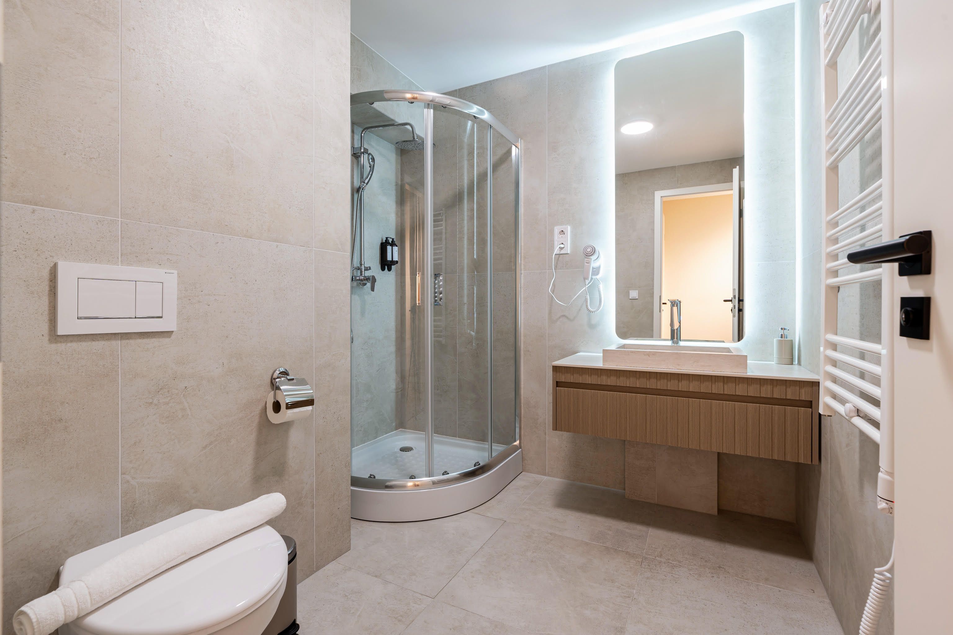 A modern bathroom with a glass-enclosed shower, a toilet, and a vanity with a mirror.