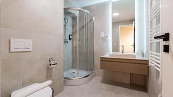 A modern bathroom with a glass-enclosed shower, a toilet, and a vanity with a mirror.
