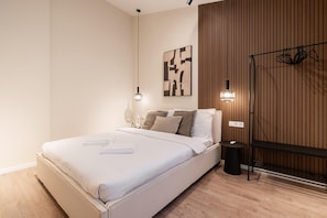 Un dormitorio moderno con cama, mesitas de noche, una lámpara de pared y un panel de pared de madera.