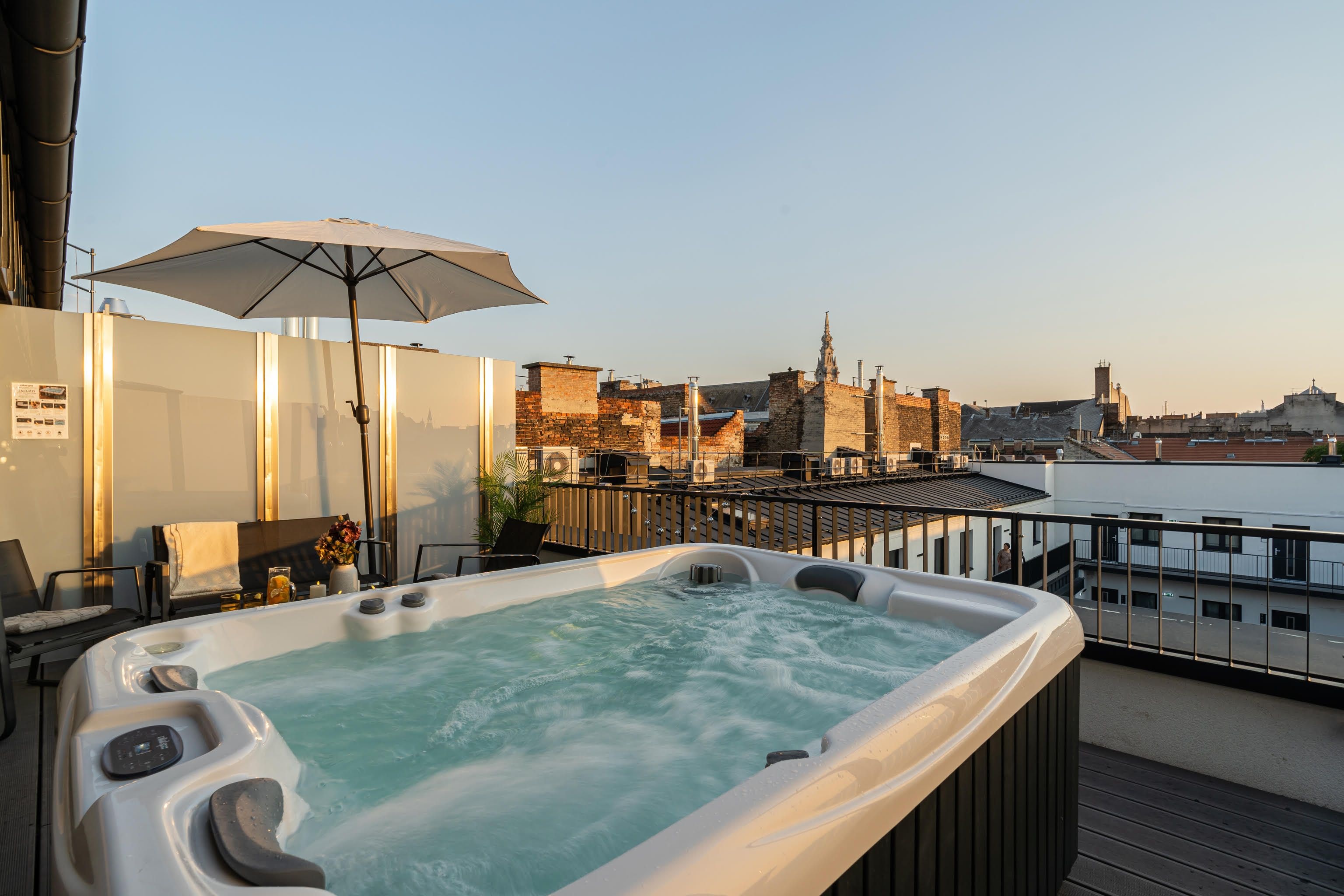 A hot tub with a city view, a table with chairs, and an umbrella.