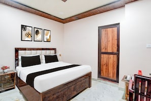 A bedroom with a bed, a wooden door, and three framed artworks on the wall. - Super OYO Hotel O Tedhi Bazaar (Ayodhya)