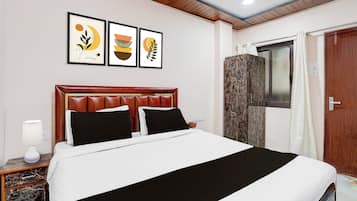 Habitación de hotel con cama, mesita de noche, lámpara y tres cuadros en la pared.