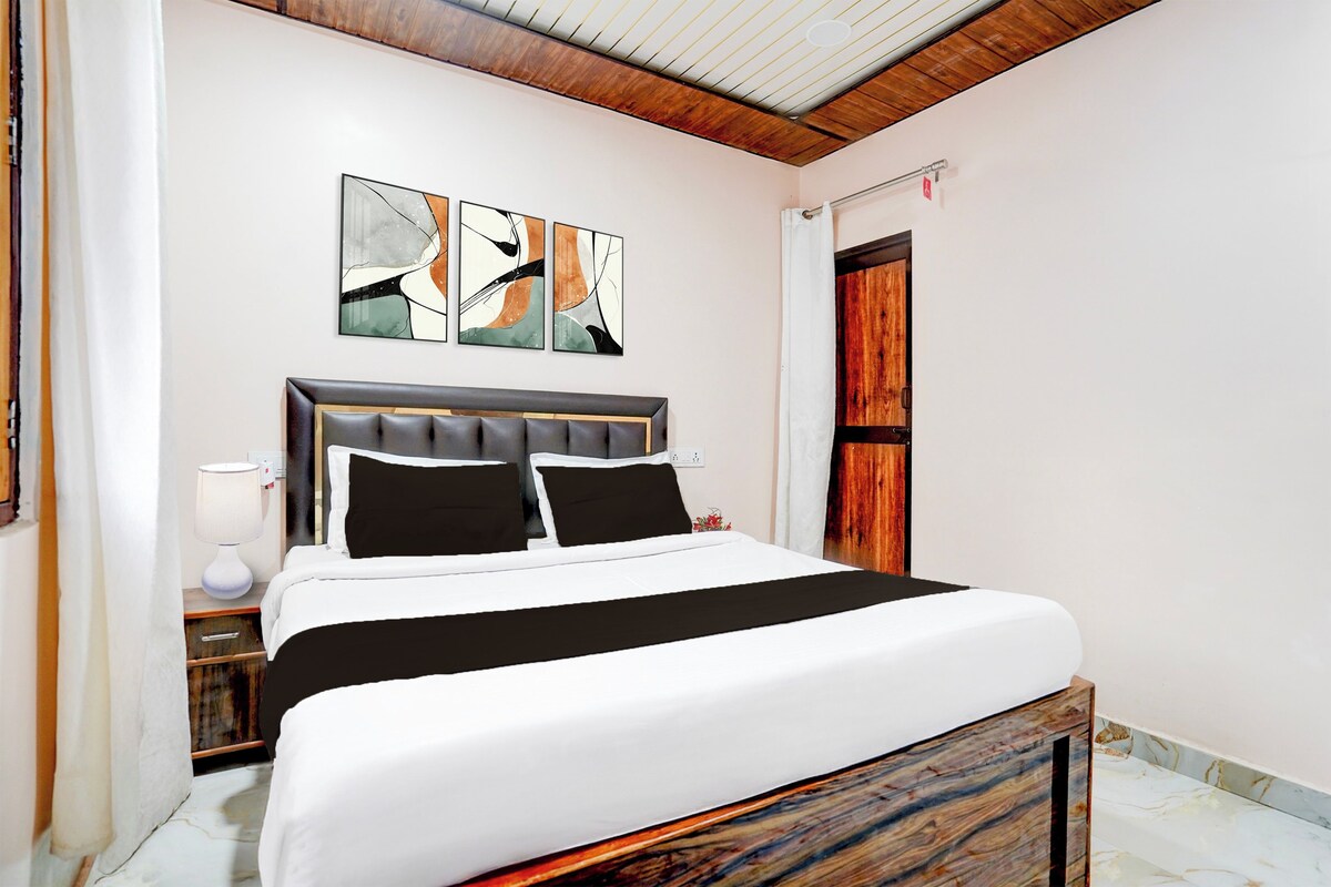 A modern bedroom with a bed, artwork on the wall, and a wooden door.
