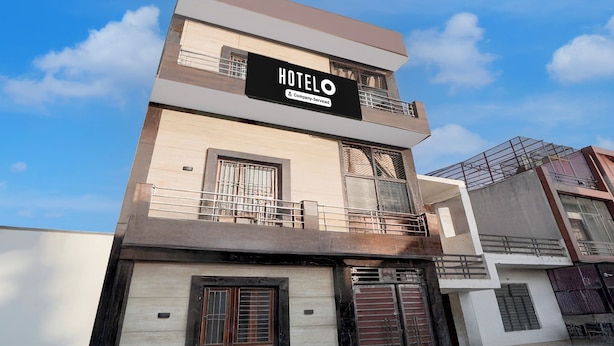 Ett hotell med en skylt som visar att det tillhandahålls tjänster för företagskunder. Hotellet har en modern design med ett platt tak och en balkong på översta våningen.