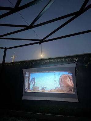 A projection screen displaying a scene with a large mechanical structure and a clear sky.