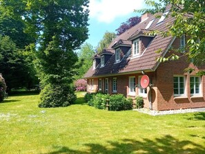 A two-story brick house with a well-maintained lawn and a large tree in the background. - Holiday Apartment in Nebel With Swimming Pool (Nebel)
