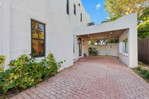 A white building with a brick pathway leading to a covered outdoor area. - Tropical 1BR Casita w/ Shared Pool Access (West Palm Beach)