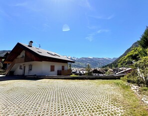 A traditional chalet with a sloped roof, a wooden staircase, and a paved courtyard. - Panoramic attic apartment in the Dolomites with a view of the mountains of Predazzo (Predazzo)