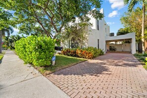 A modern house with a brick pathway leading to a covered entrance. - Tropical 3BR Oasis w/ Pool (West Palm Beach)