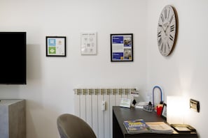 A reception area with a clock, framed welcome signs, a desk with a lamp, and a chair. - Alice’s House Apartment with Balcony, Wi-Fi, and Air Conditioning (Roma)