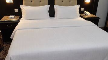 A hotel room with a large bed, two bedside tables, a wall-mounted telephone, and a painting above the bed.