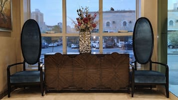 A reception area with a bench, a vase with flowers, and a view of the street through large windows.