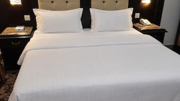 A hotel room with a large bed, two bedside tables, a wall-mounted telephone, and a painting above the bed.