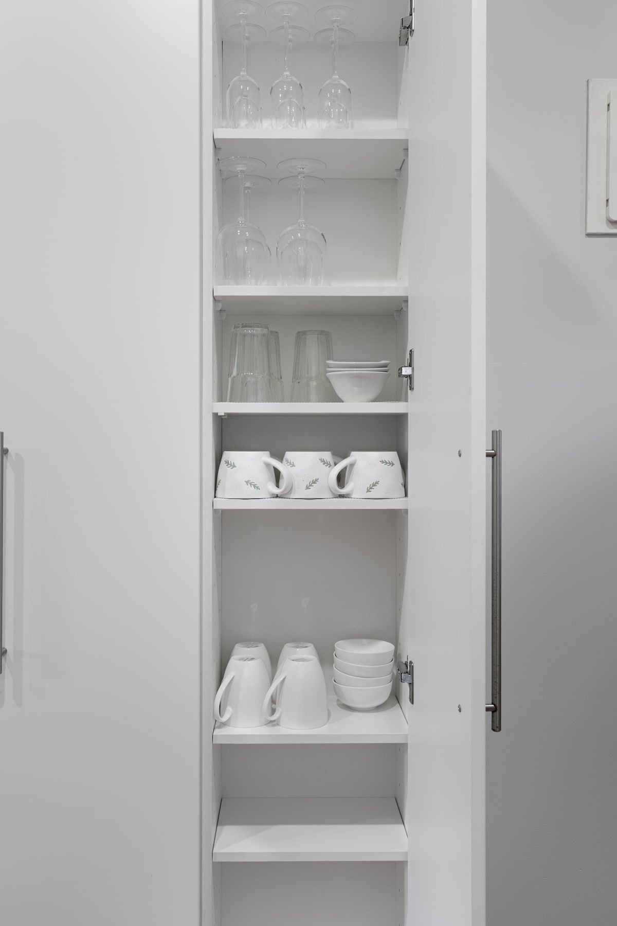A white interior with a cabinet containing glassware, plates, and cups.