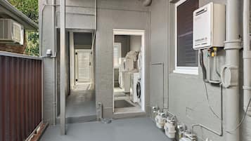 A laundry area with a washing machine, dryer, and a water heater labeled 'THERMANN 26'.