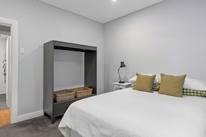 A bedroom with a bed, a wardrobe, a nightstand, and a lamp.