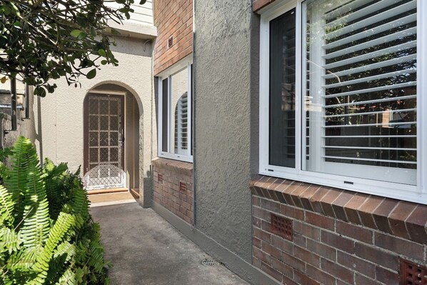 A residential building with a brick facade, a covered entryway, and a window with blinds.