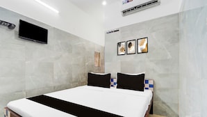 Quarto de hotel moderno com uma cama grande, televisão de tela plana na parede e um pequeno aparelho de ar condicionado.